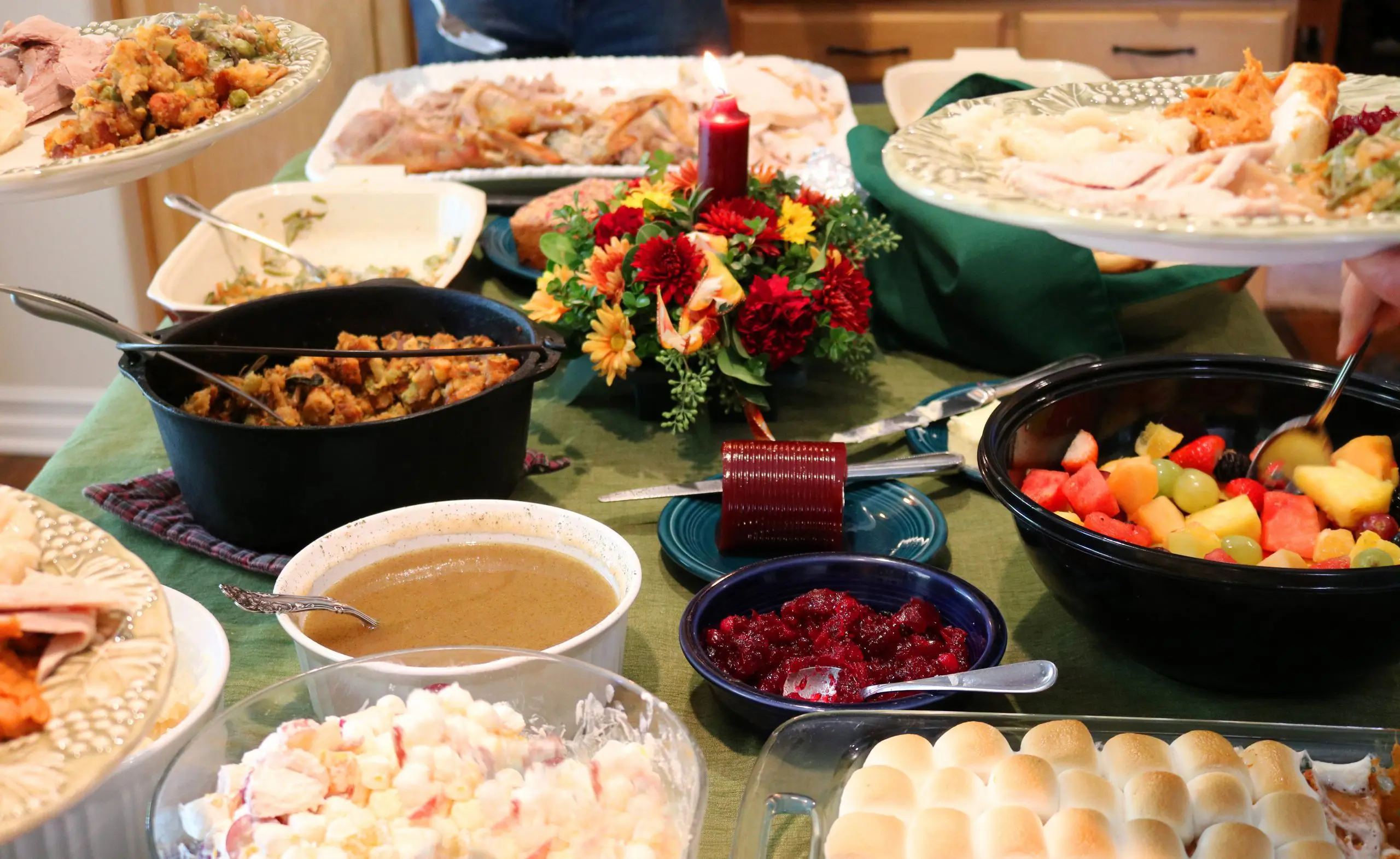 A Thanksgiving table crowded with platters, gravy, cranberry sauce and rolls
