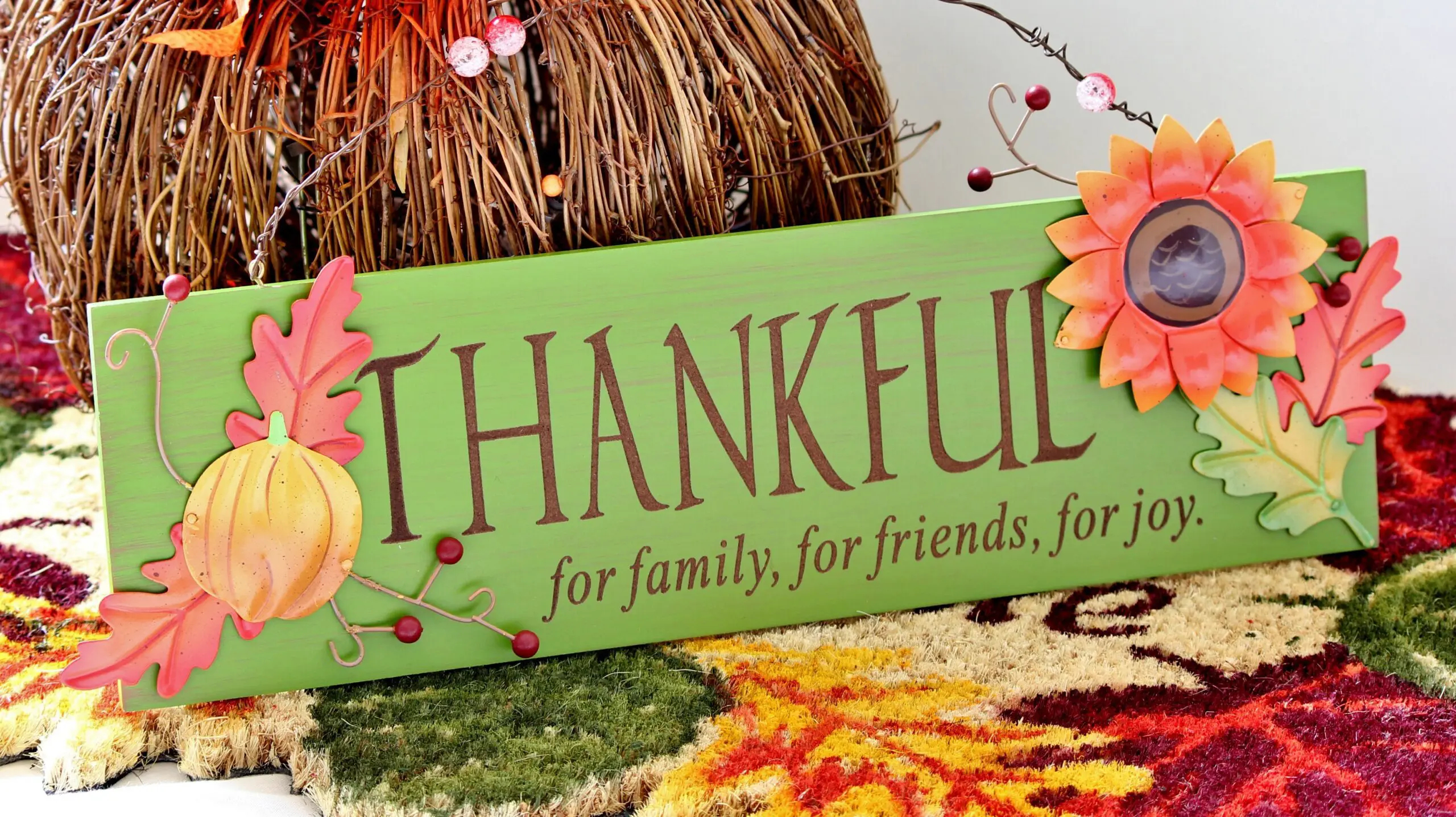 A painted THANKFUL sign among autumn leaves and gourds