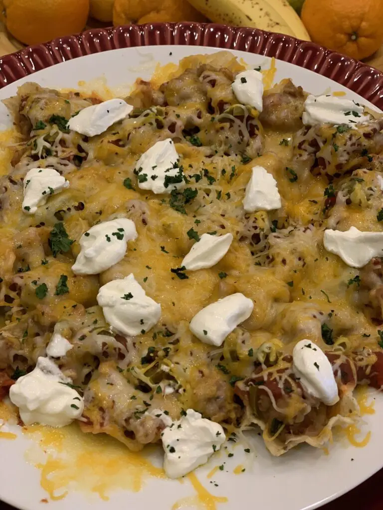 Melted sharp cheddar cheese stretching beautifully between a single tortilla chip and a massive platter of nachos