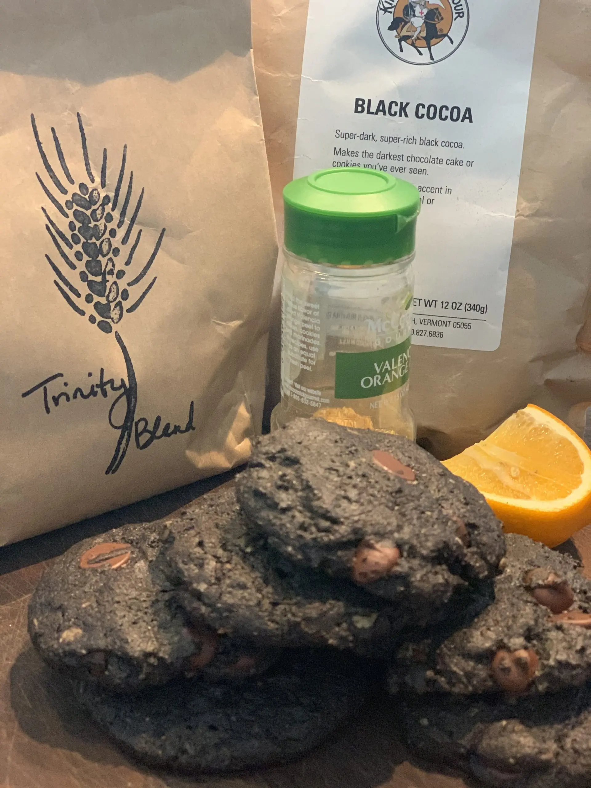 Dark black-cocoa cookies beside the flour and cocoa they were made from