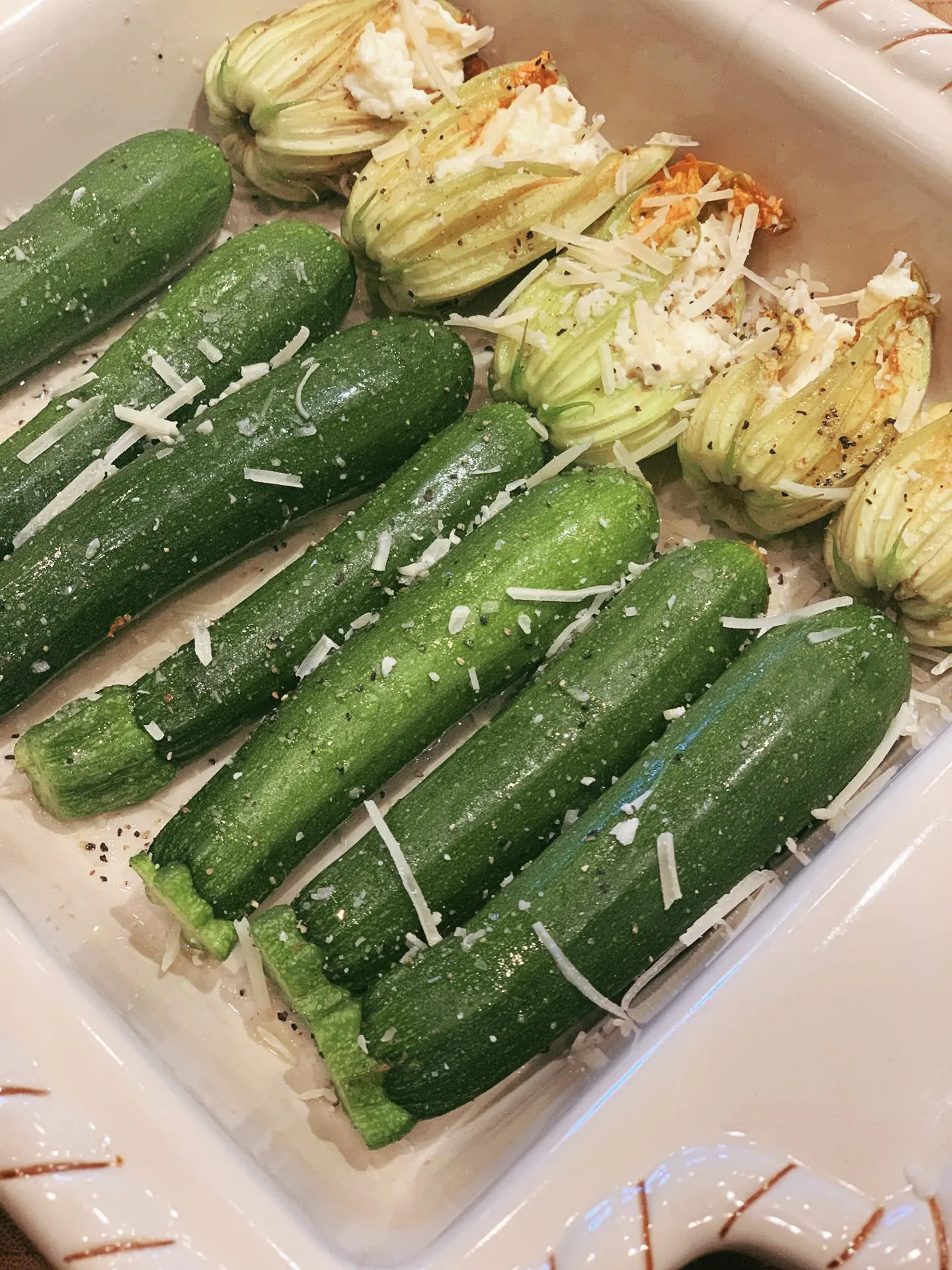 Zucchini and stuffed squash blossoms in a white baking dish