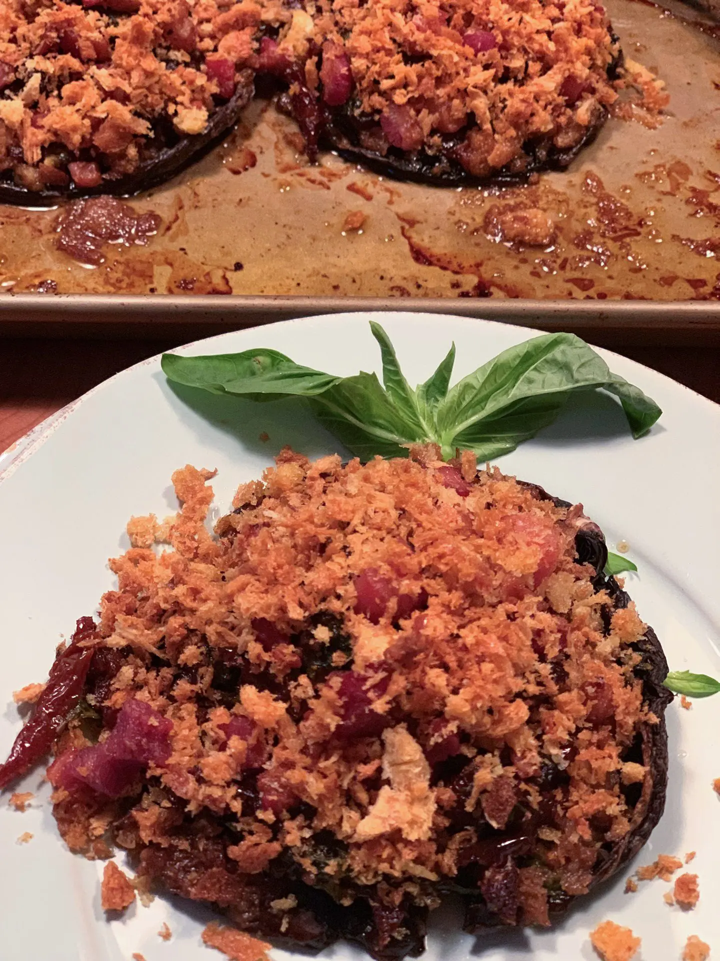 A stuffed portobello plated with fresh basil, the tray behind it