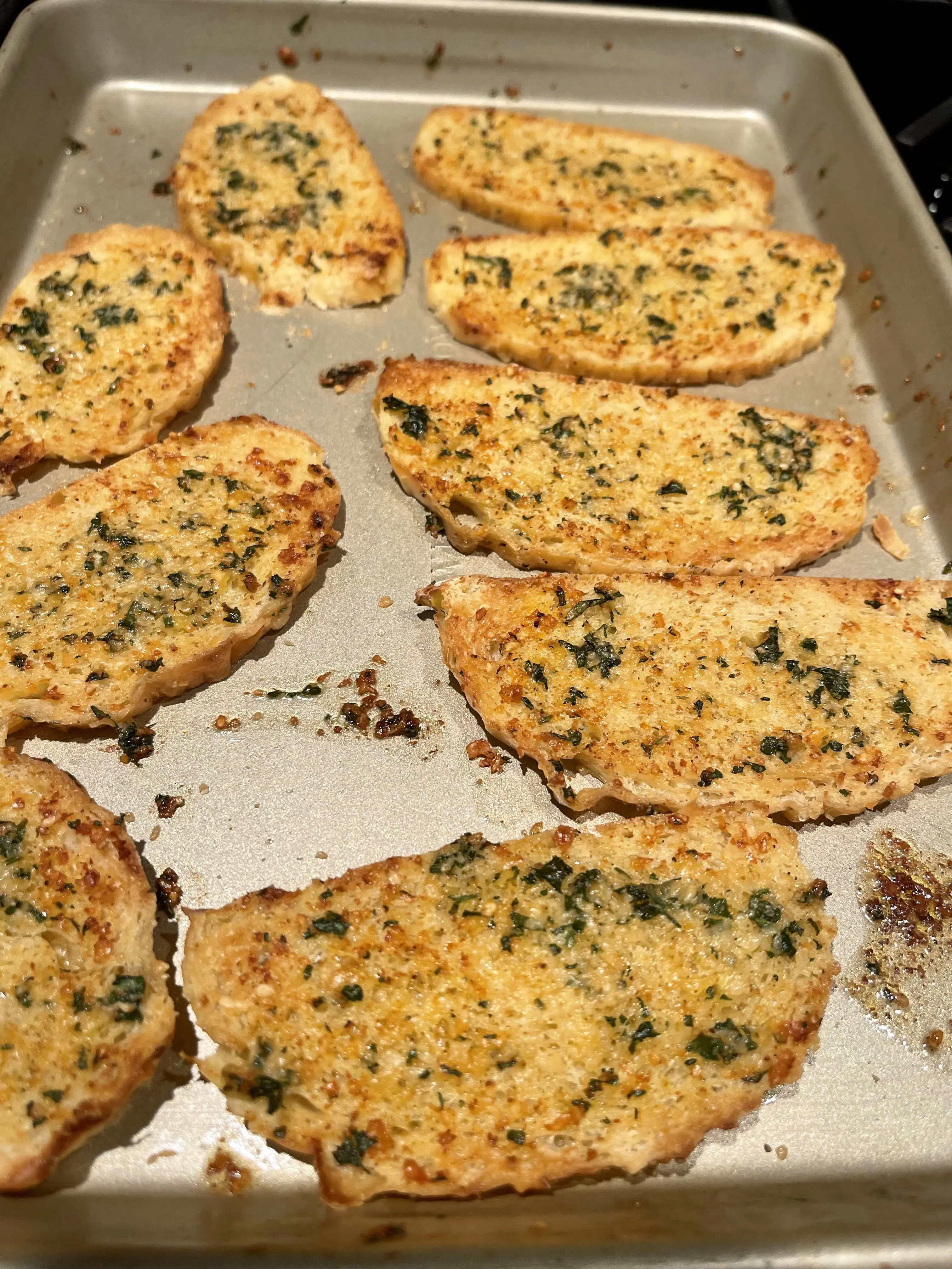 Sliced dinner rolls brushed with herb butter and broiled on a sheet pan