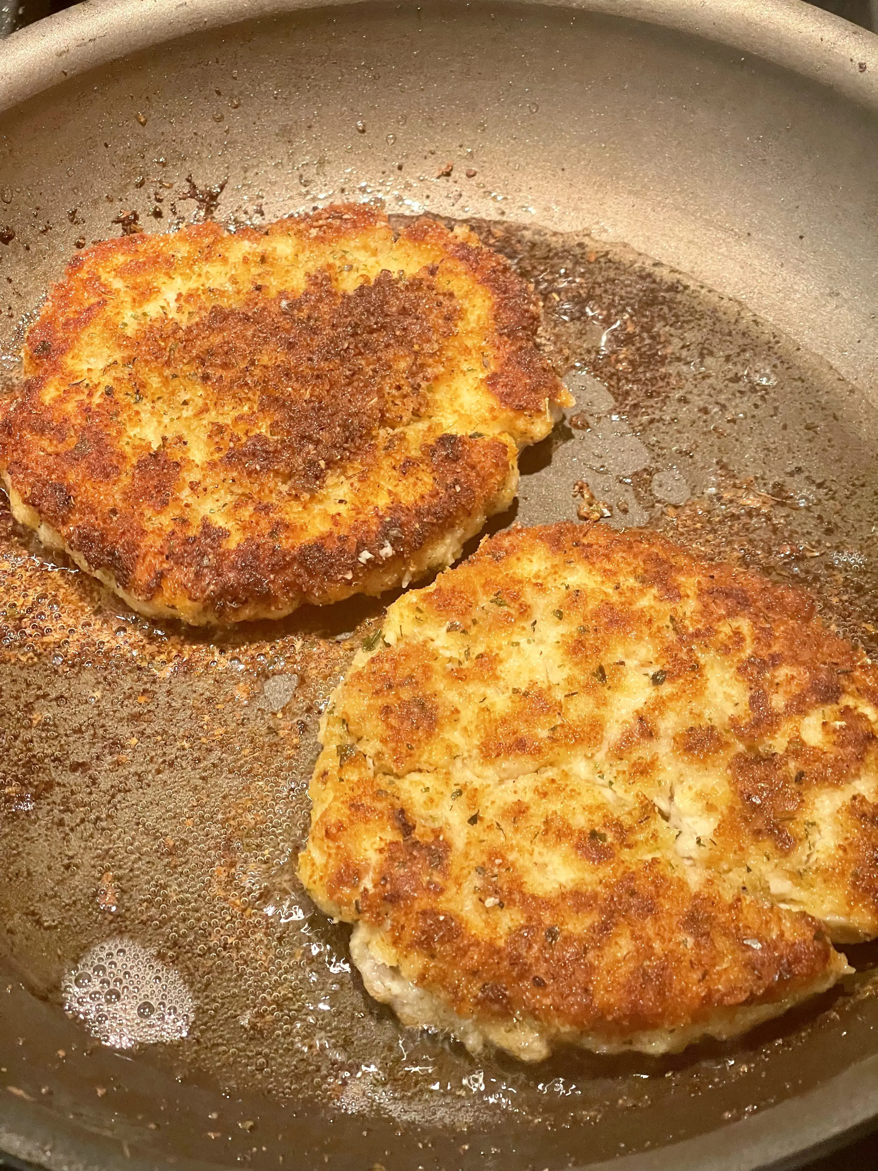 Two turkey cakes browning in a skillet