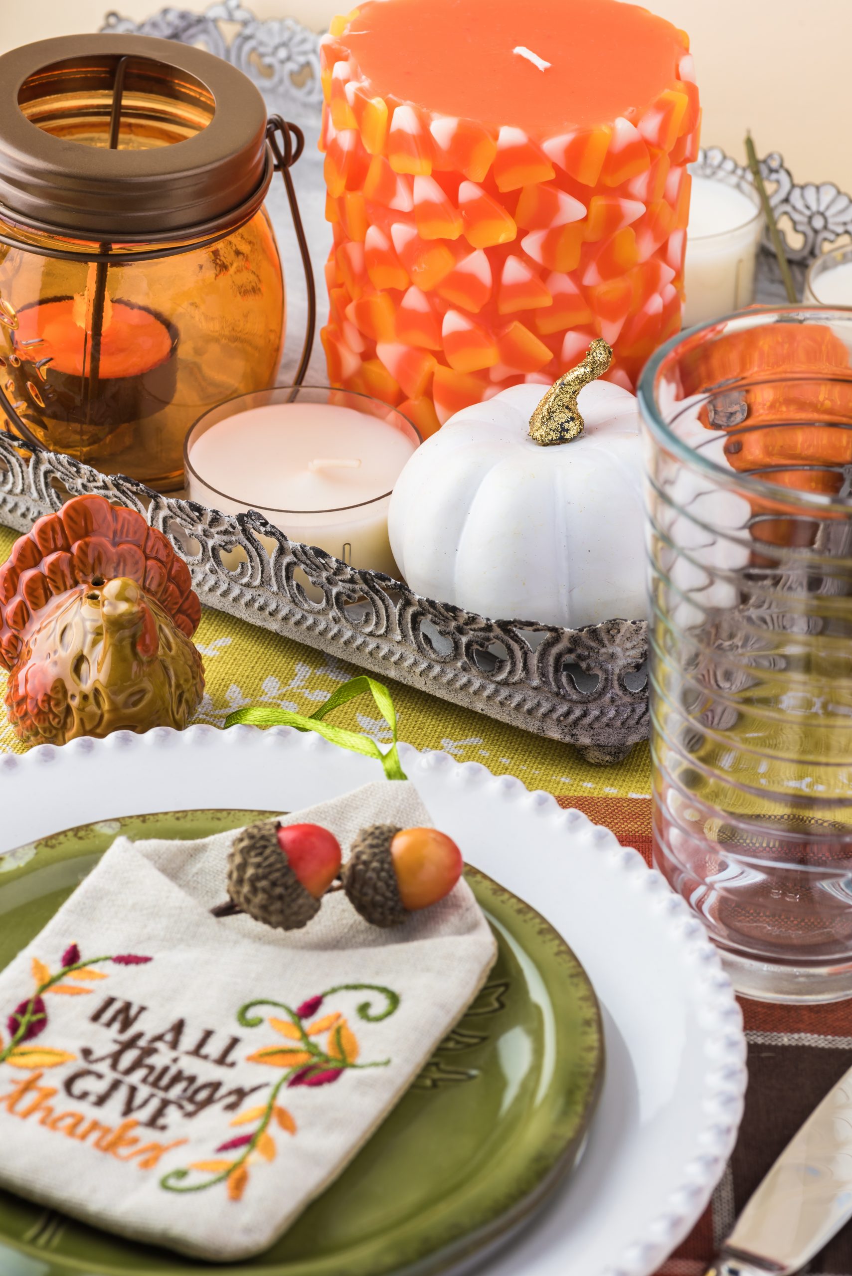 Close up of tableset with colorful plates, silverware and center piece arrangement for Thanksgiving party.