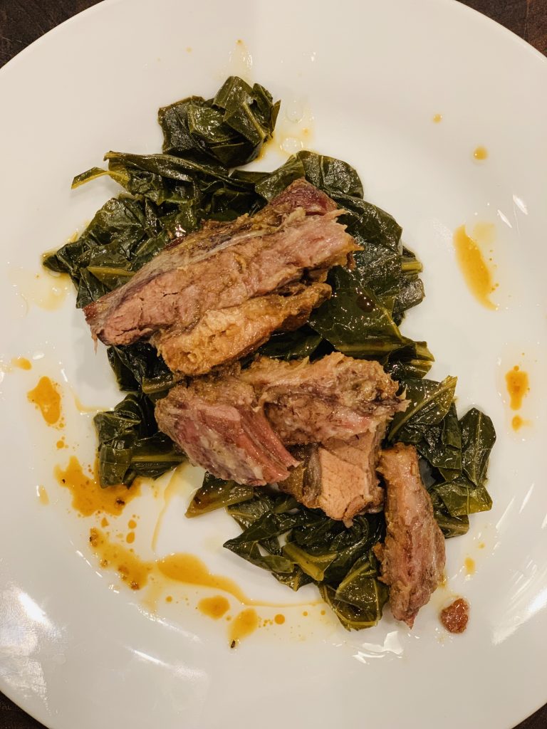 Dark, syrupy collard greens and thick, caramelized chunks of slow-roasted pork belly bubbling in a cast-iron Dutch oven