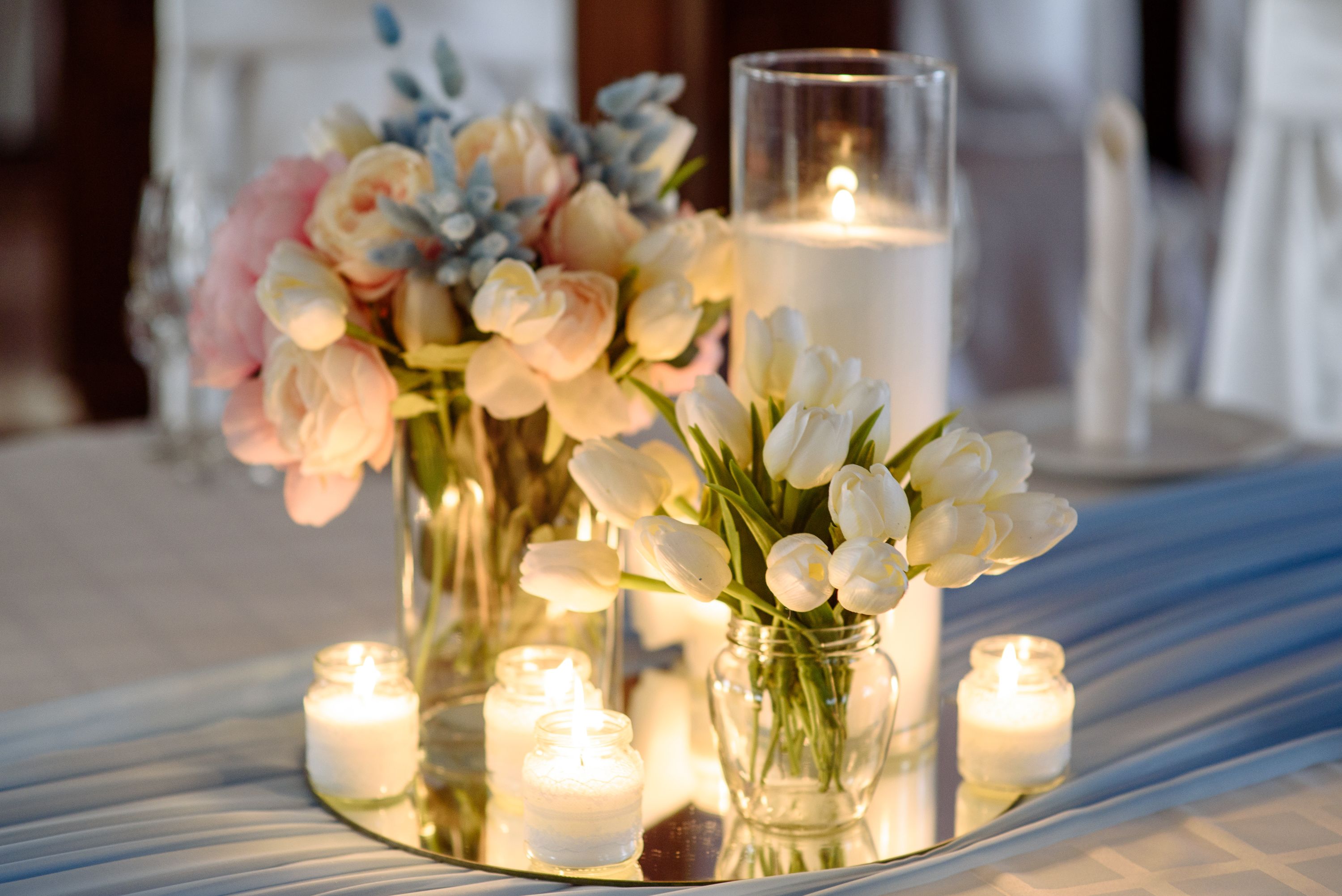 Wedding decorations. Fresh spring tulips and candles in glasses. Covered festive table. Bride idea.