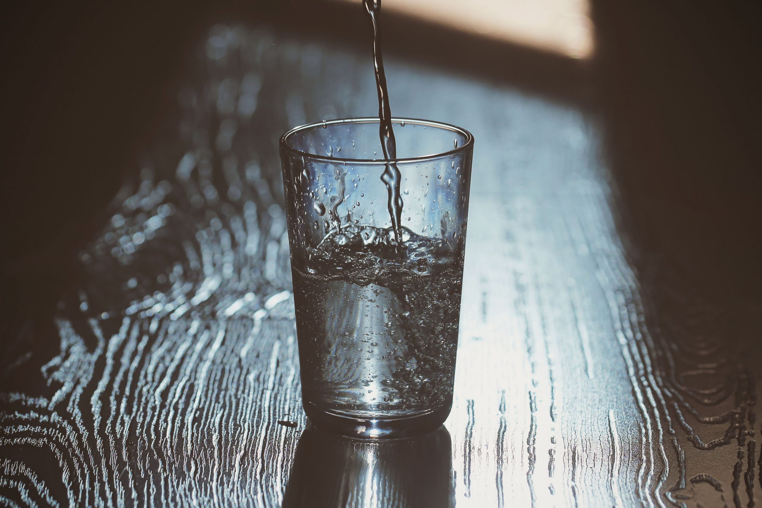 A bright, encouraging image of a glass half-filled with fresh water resting gracefully before a storm.